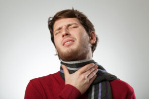 Man in scarf suffering from sore throat